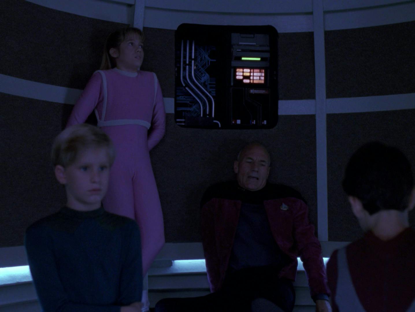 Trapped in the turbolift without any power, Captain Picard sits on the floor after injuring himself surrounded by three bored kids in 'Disaster'