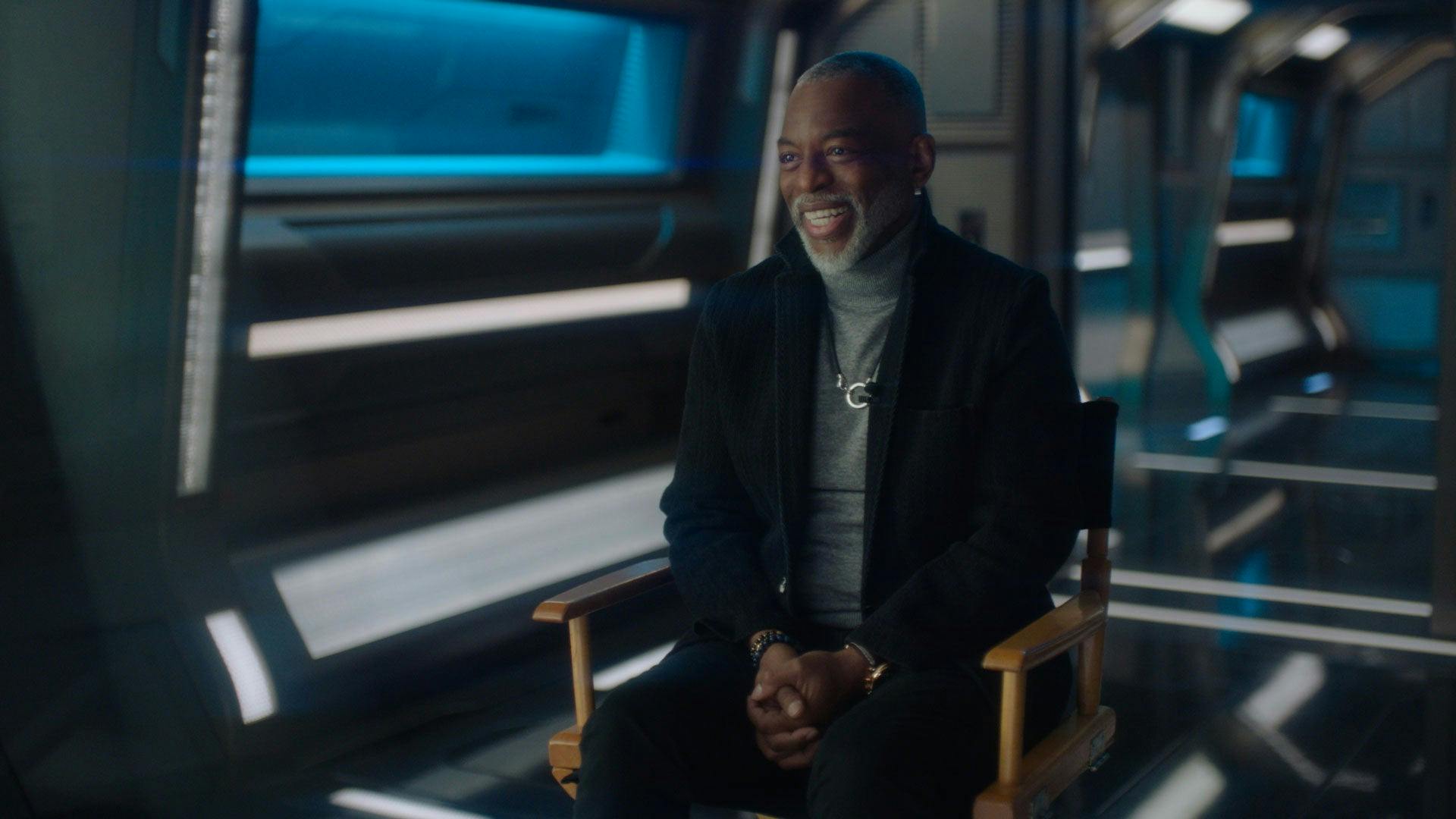 LeVar Burton on the set of Star Trek: Picard sitting in a tall director's chair and smiling