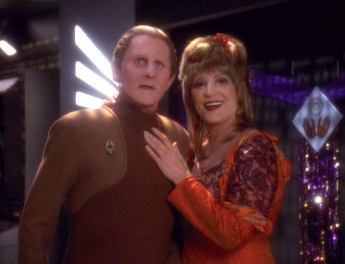 Lwaxana Troi stands beside Odo with her hand on his chest in 'Fascination'