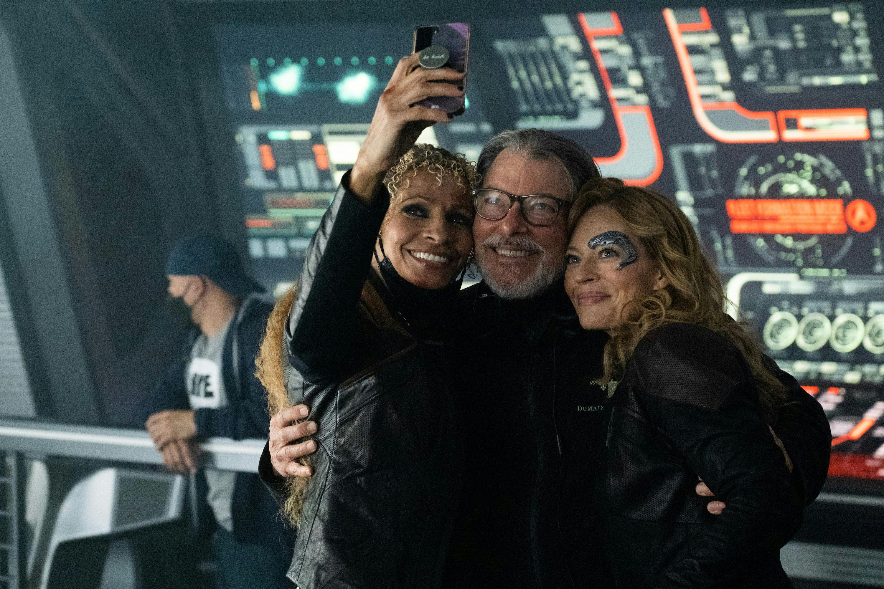 Star Trek: Picard BTS still - Michelle Hurd, Jonathan Frakes, and Jeri Ryan take a selfie on the Titan bridge set