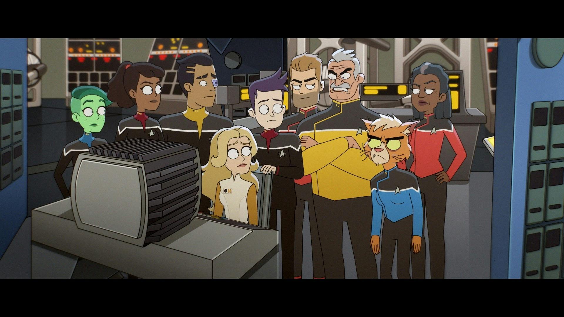 The ensigns and bridge crew gather around a computer.