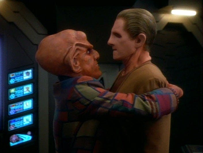 Quark embraces Odo in a hug as Odo stiffens up on Star Trek: Deep Space Nine
