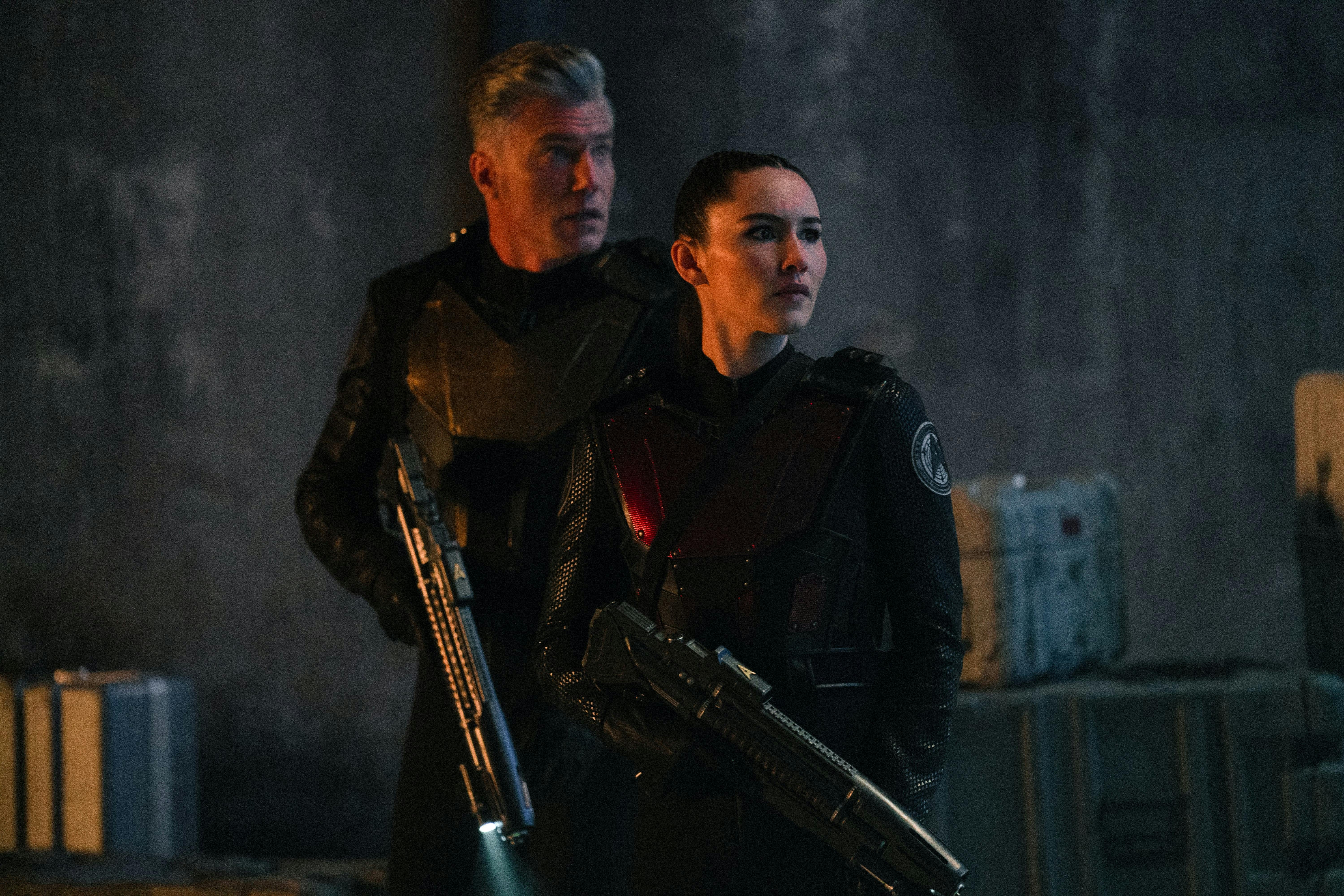 Pike (Anson Mount) and La'An (Christina Chong) stand next to each other. Both are in tactical gear and holding phaser rifles.