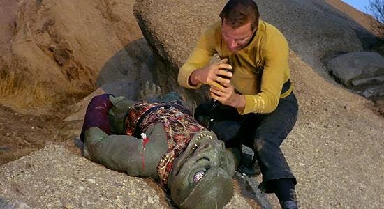 Kirk stands over the bloodied body of the Gorn after his attack with an explosive on Star Trek: The Original Series' Arena
