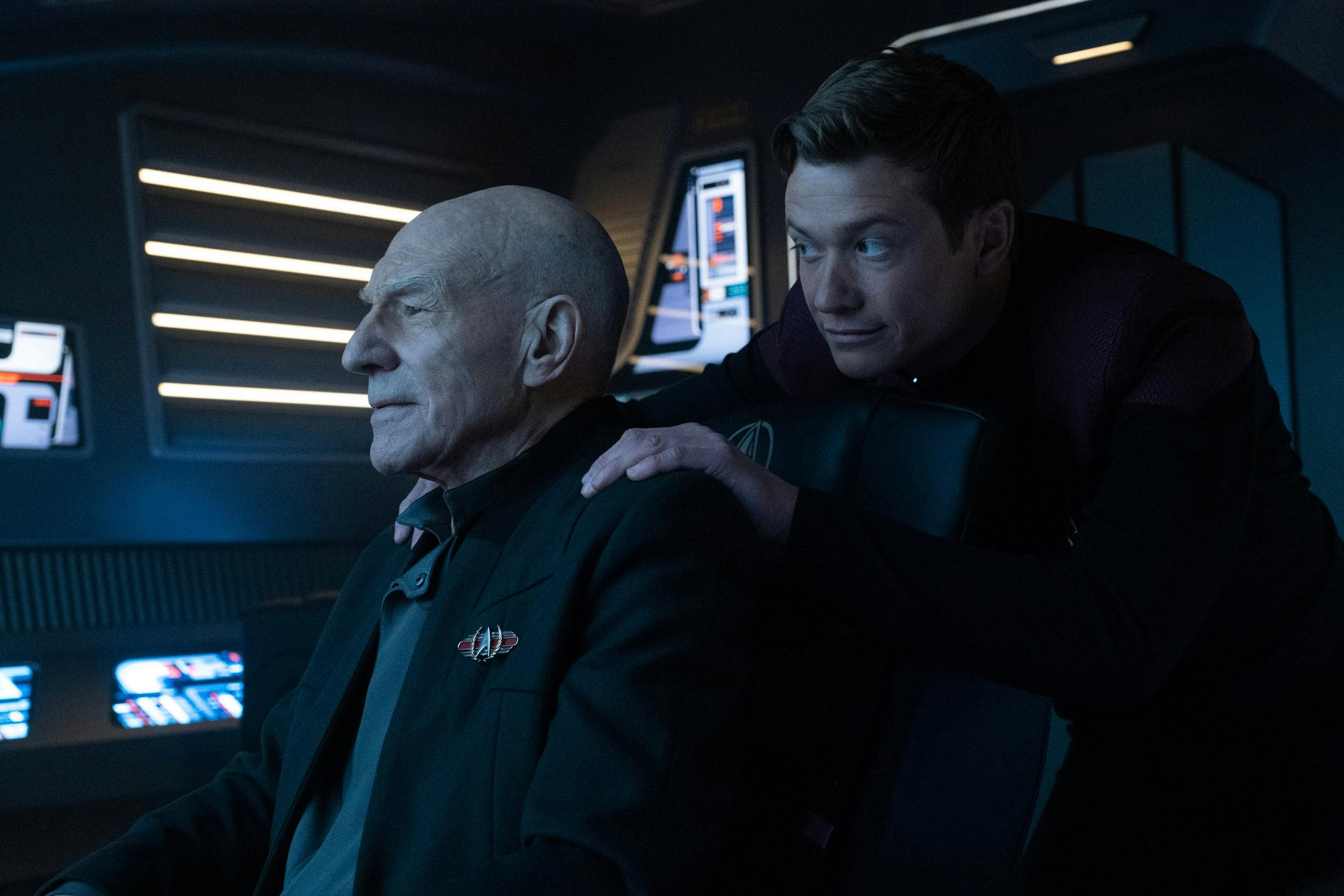On a shuttle, Jean-Luc Picard looks ahead, touched by what he sees, as Jack Crusher crouches behind him with his hands on his father's shoulders in 'The Last Generation'