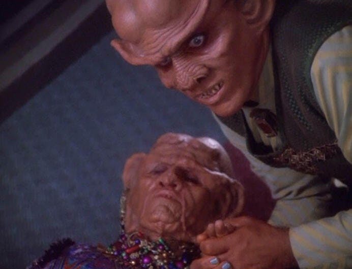 A stressed Quark grasps his mother's hand after an unconscious Ishka suffers a heart attack and is laying on the floor in 'Profit and Lace'