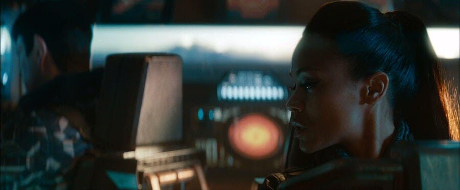 In a shuttle, Uhura looks over her shoulder towards Spock in Star Trek Into Darkness