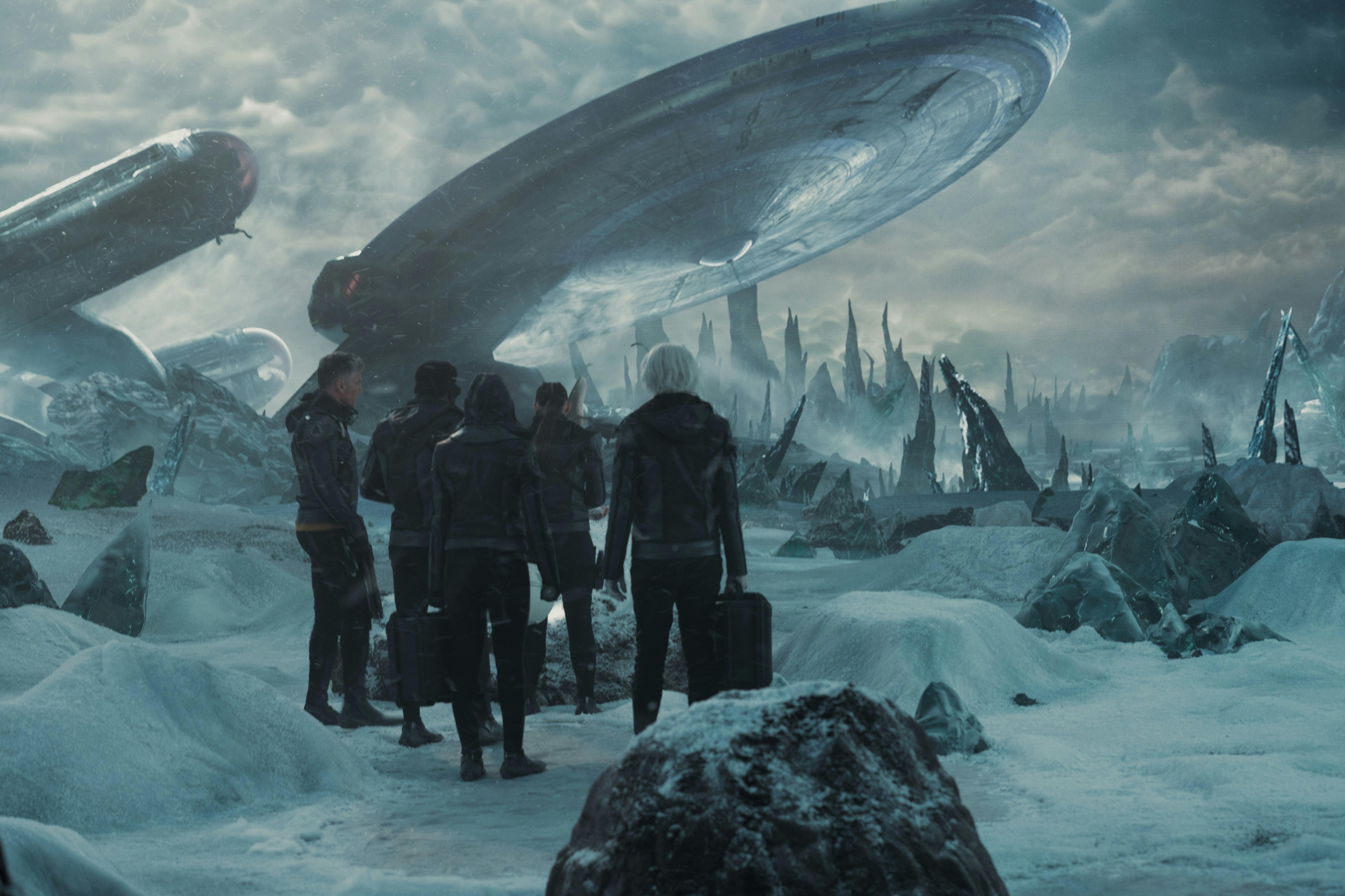 A large group looks at a crashed starship on a snowy planet.