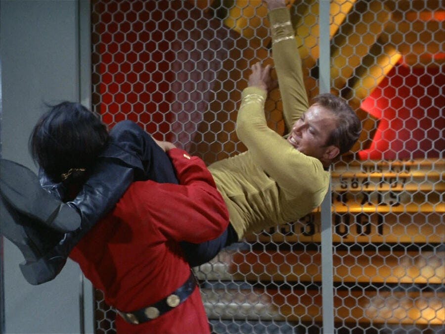 Clinging to a fence, Kirk grabs Khan by wrapping his legs around his neck in 'Space Seed'