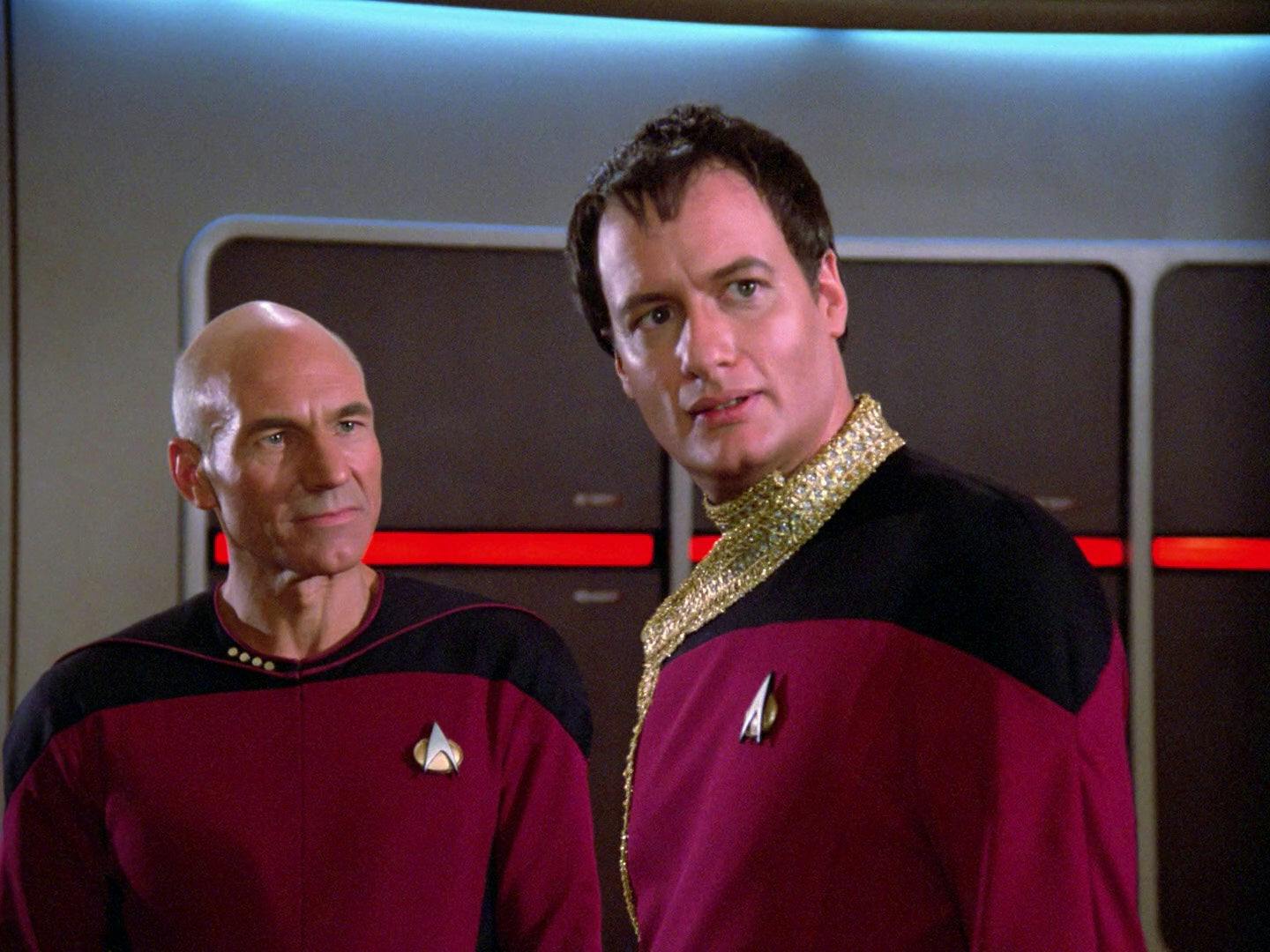 On the bridge of the Enterprise, Picard looks over at Q who stands before him dressed in a Starfleet uniform with ornate detail in 'Hide and Q'