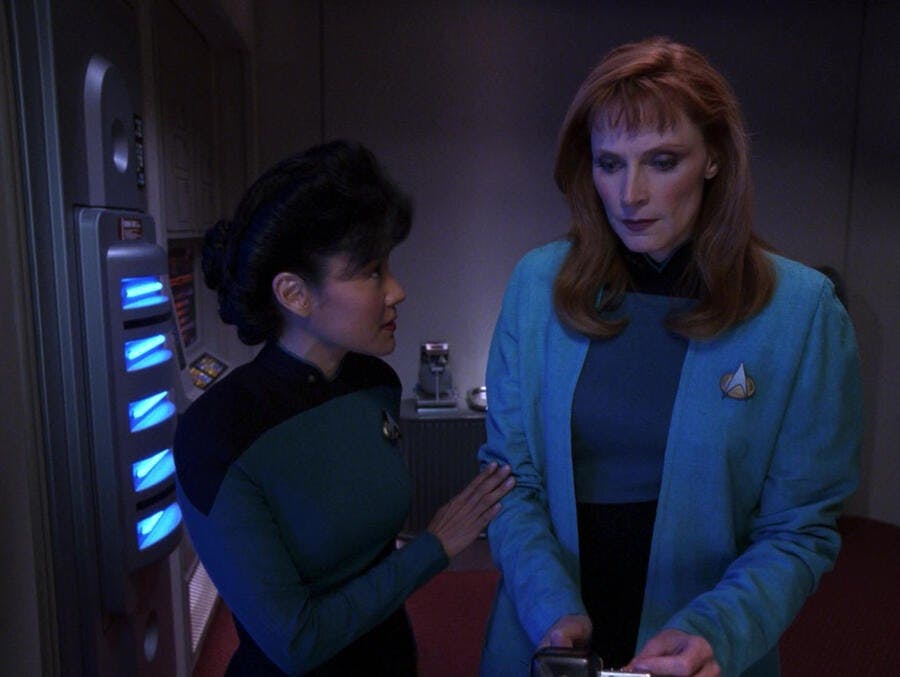 Nurse Alyssa Ogawa places a reassuring hand on Dr. Beverly Crusher's arm in 'Suspicions'