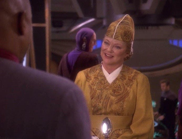 Louise Fletcher as Kai Winn Adani on Star Trek: Deep Space Nine looking at Avery Brooks as Sisko with his back to us