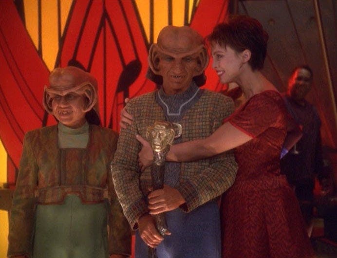 Rom, after being appointed Grand Nagus, is embraced by Leeta. Nog stands at his side.