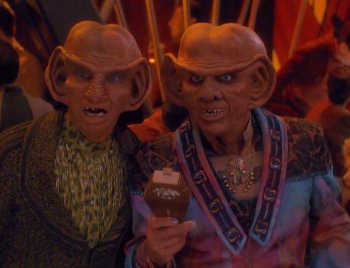 At the busy bar, Rom and Quark standing side-by-side express shock in 'Family Business'