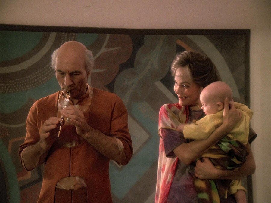 Picard as Kamin plays his Ressikan flute while his wife Eline holds their son Batai in 'Inner Light'