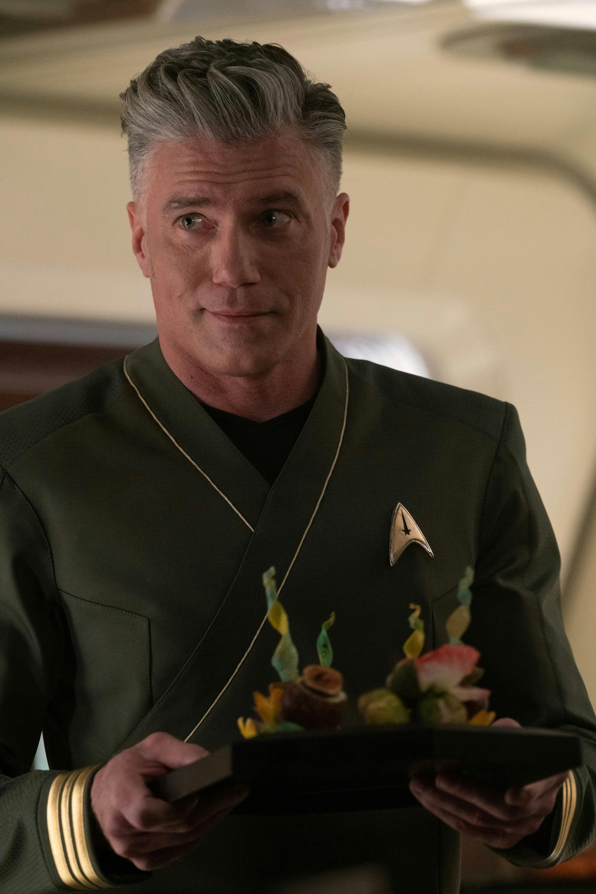 Captain Pike, in his green formal command shirt, carries a tray of crudite in 'Charades'