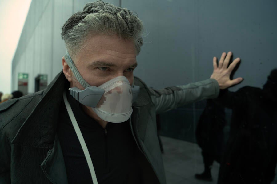Captain Pike leans against a glass-paneled building as he struggles to breathe in his oxygen mask in 'Ad Astra per Aspera'