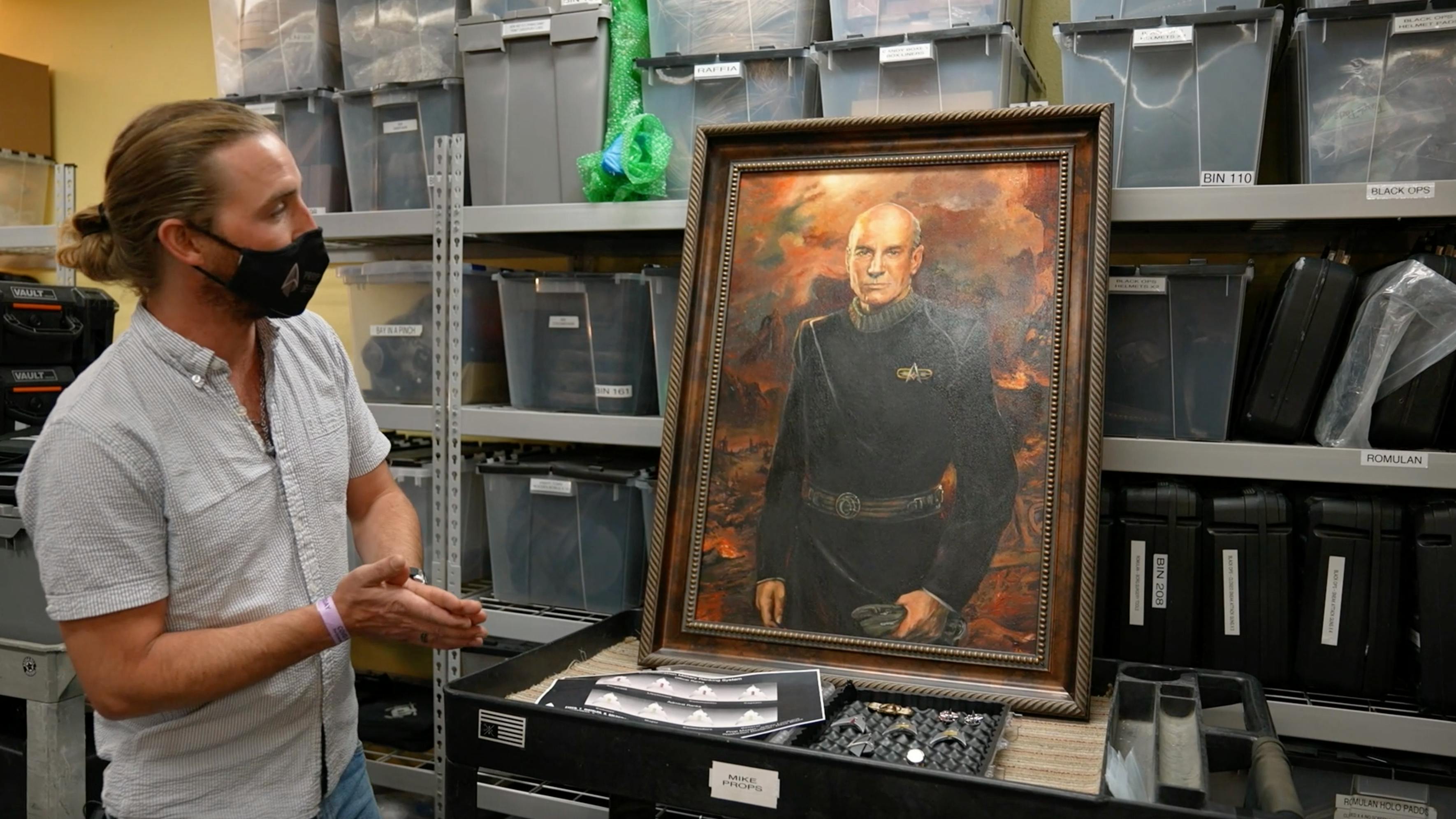 The propmaster for Star Trek: Picard Season Two stands near a prop portrait of Picard from the alternate universe.