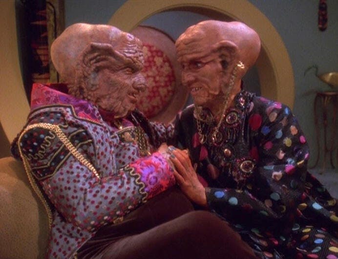 The Grand Nagus Zek and Ishka look into each other's eyes as they clasp hands in 'Ferengi Love Songs'