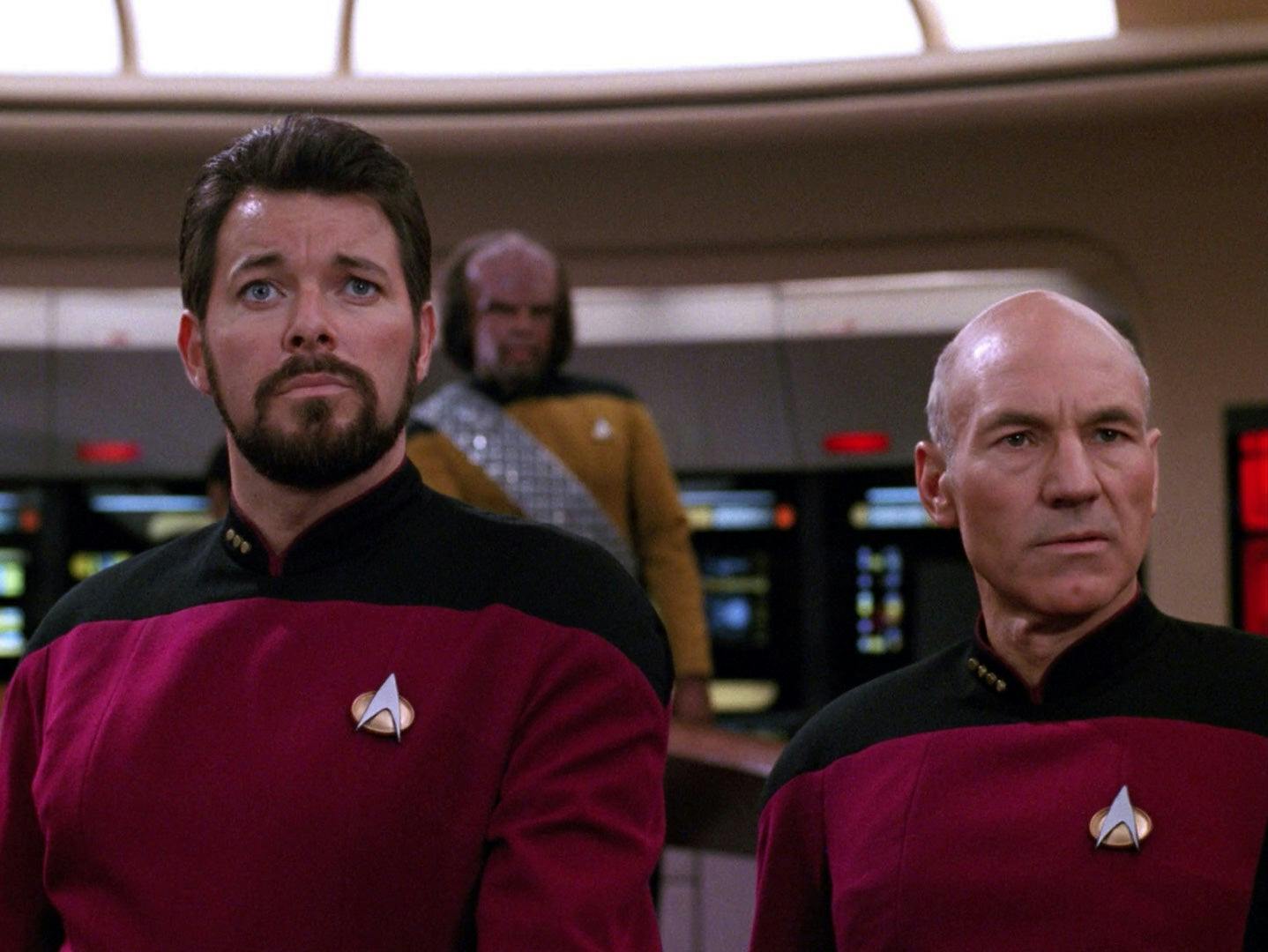 Captain Picard and Will Riker stare at the Enterprise-D's viewscreen.