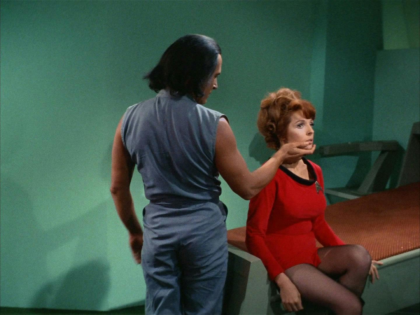 A standing Khan grasps Marla McGivers' face in his hand in a patronizing way in Space Seed