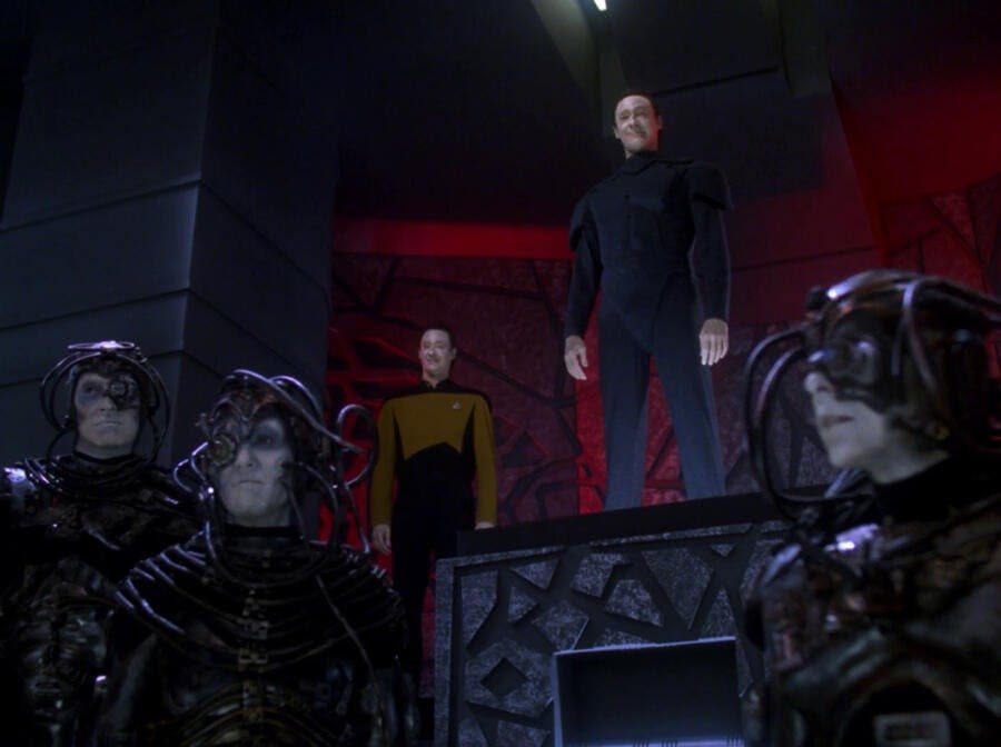 On a platform, Data stands with his brother Lore, with the group of altered Borg below them in 'Descent, Part I'