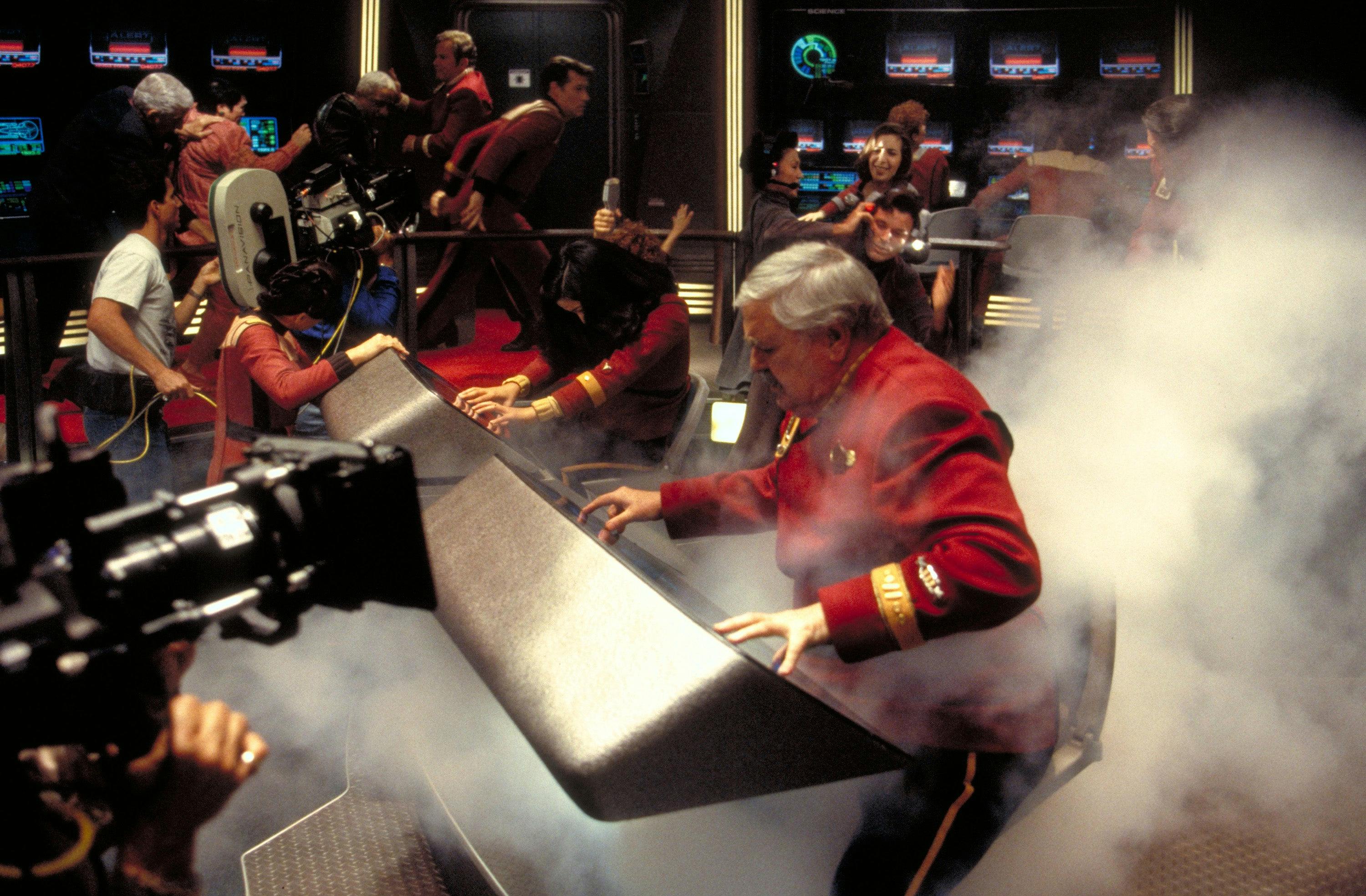 James Doohan at the controls as smoke arises around him on set of Star Trek Generations