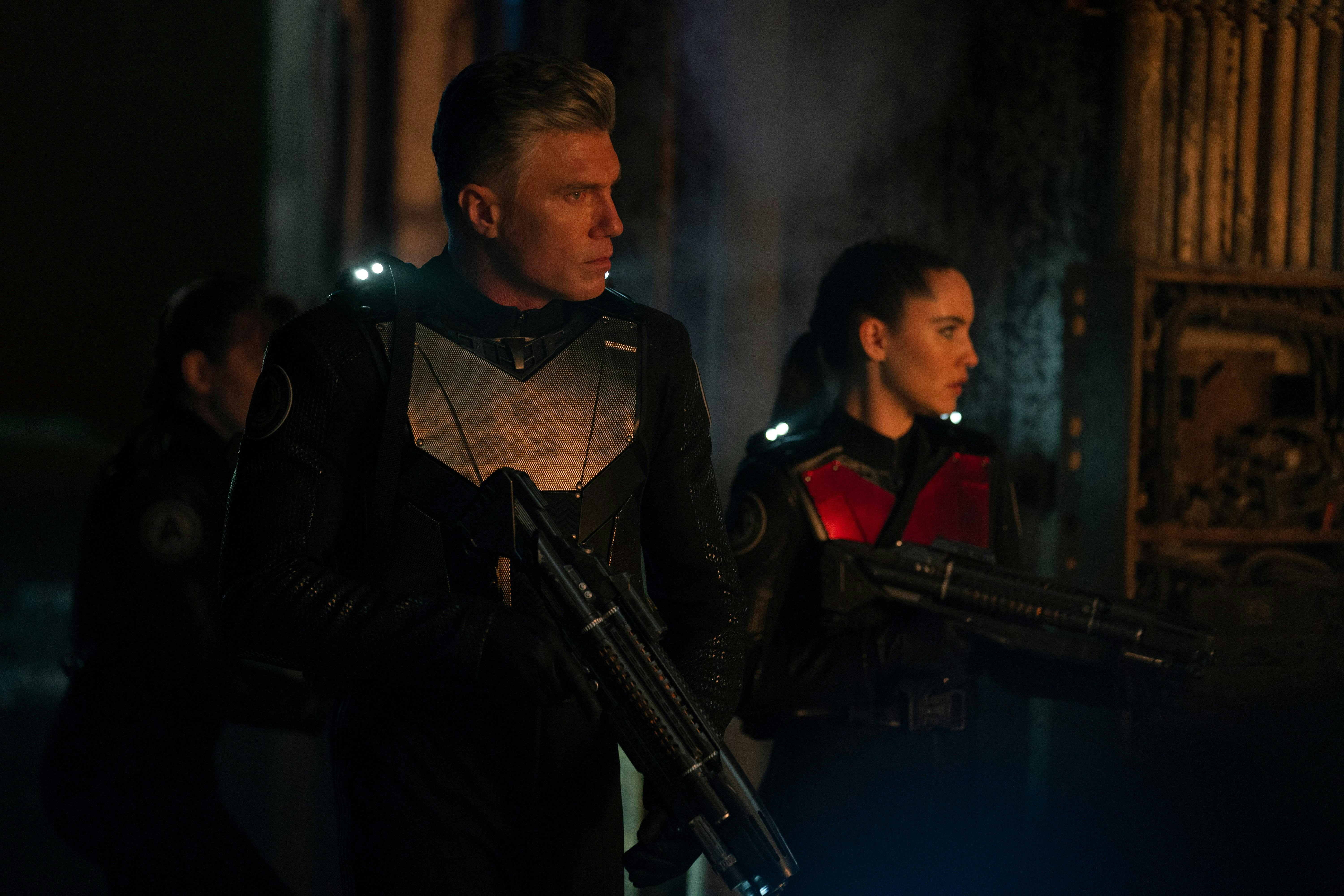 Captain Pike (Strange New Worlds) and La'An wear tactical uniforms and hold phaser rifles. They are looking around.