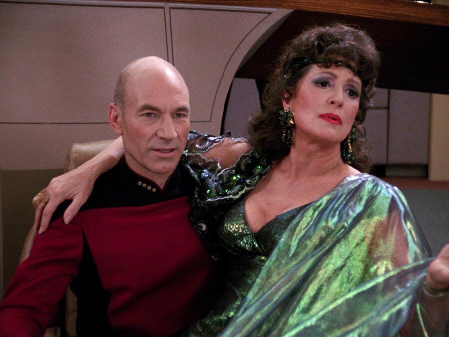 Lwaxana Troi sits on Captain Jean-Luc Picard's lap in 'Ménage à Troi'