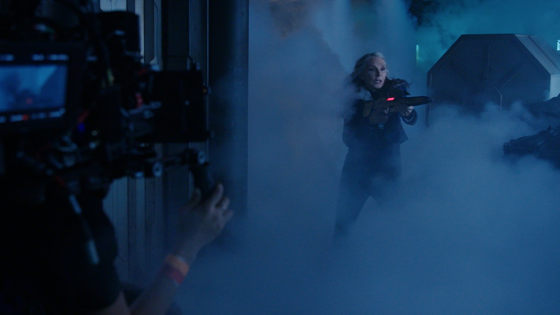 BTS still of Gates McFadden as Beverly Crusher holding a phaser on Star Trek: Picard