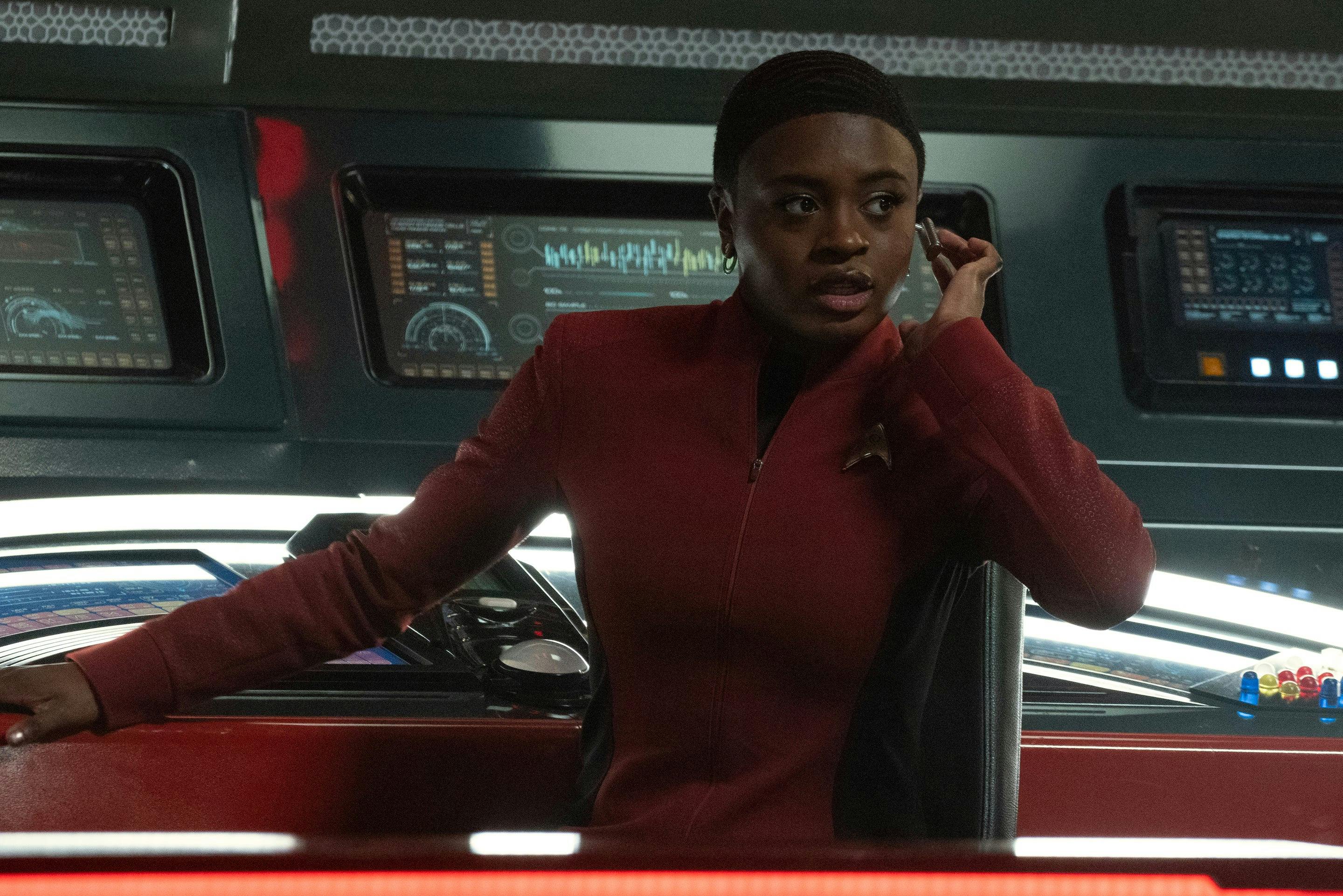 At comms, Uhura looks over at touches her earpiece