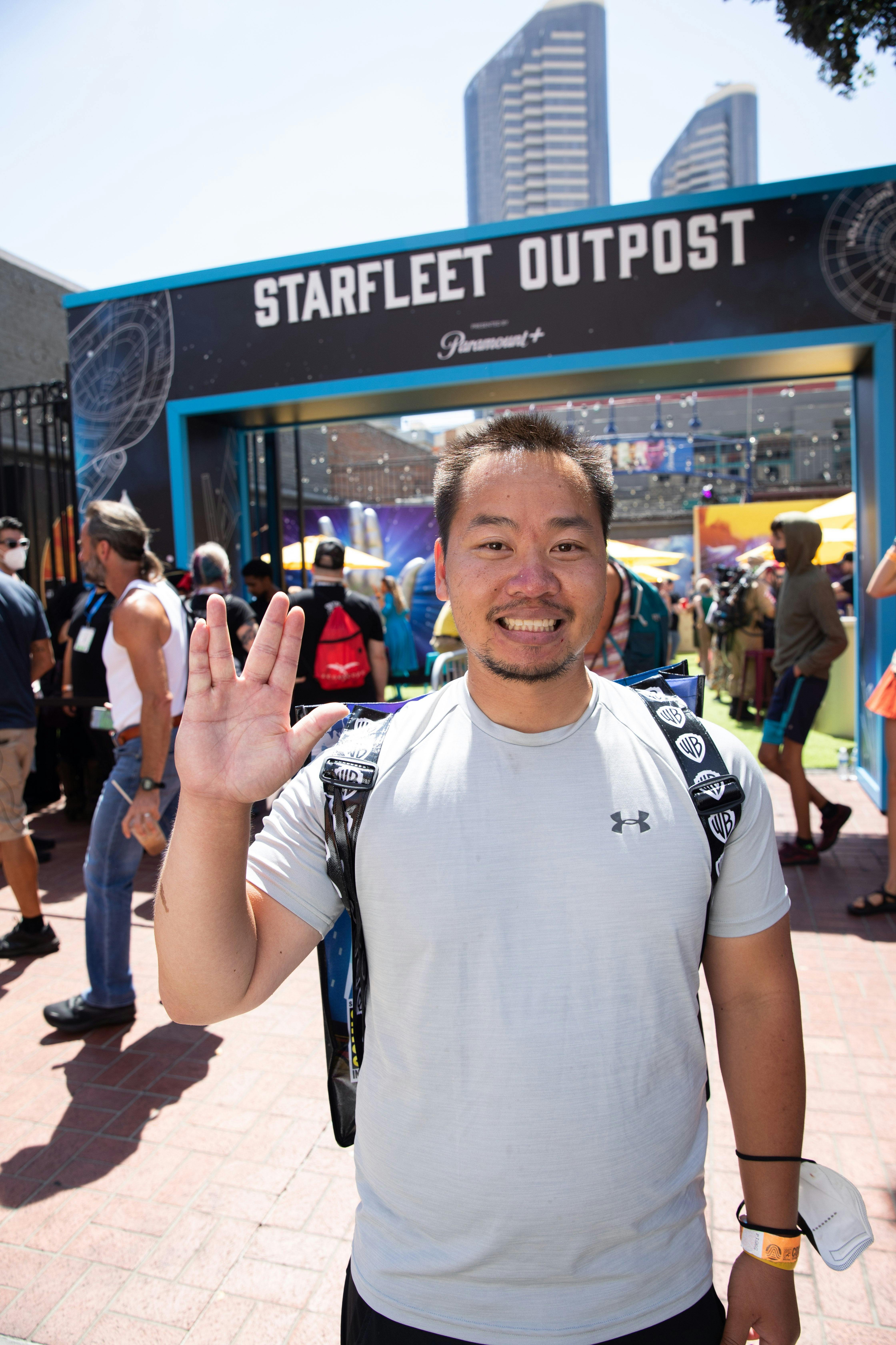A fan smiles and gives the Vulcan salute at the entrance to the Starfleet Outpost.