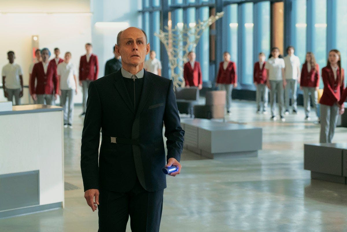 A school principal stops in his tracks to witness the monitor before him as students begin to crowd around in the common area of 'Children of Mars'