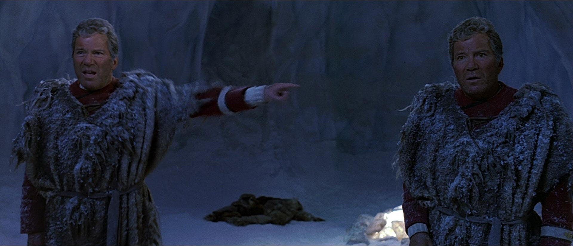 Two versions of James T. Kirk stand opposite each other. The Kirk on the left is pointing at the Kirk on the right. Both are wearing snowy clothes and are standing on an icy planet.