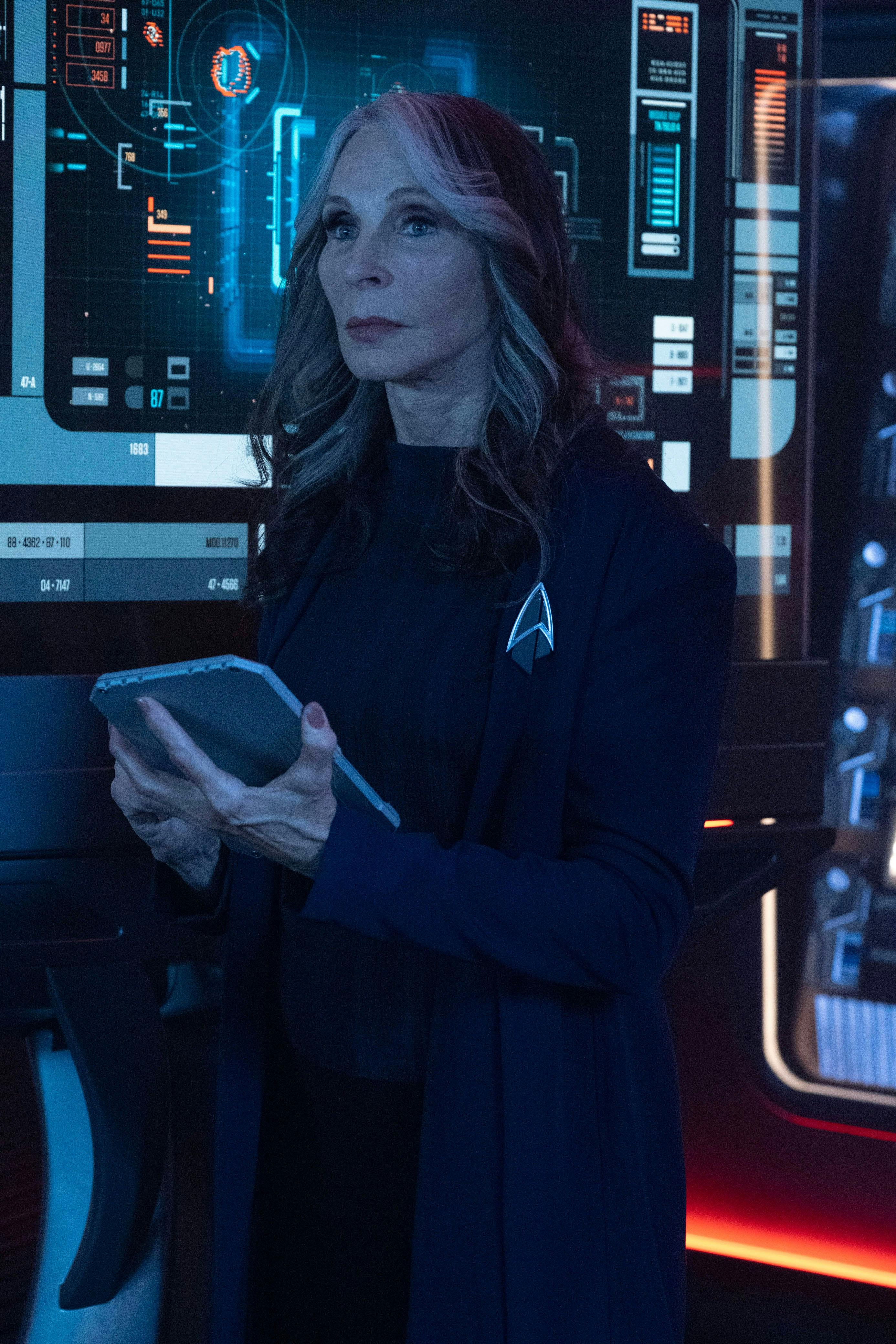 A concerned Dr. Beverly Crusher holds her med padd in hand as she looks forward on Star Trek: Picard