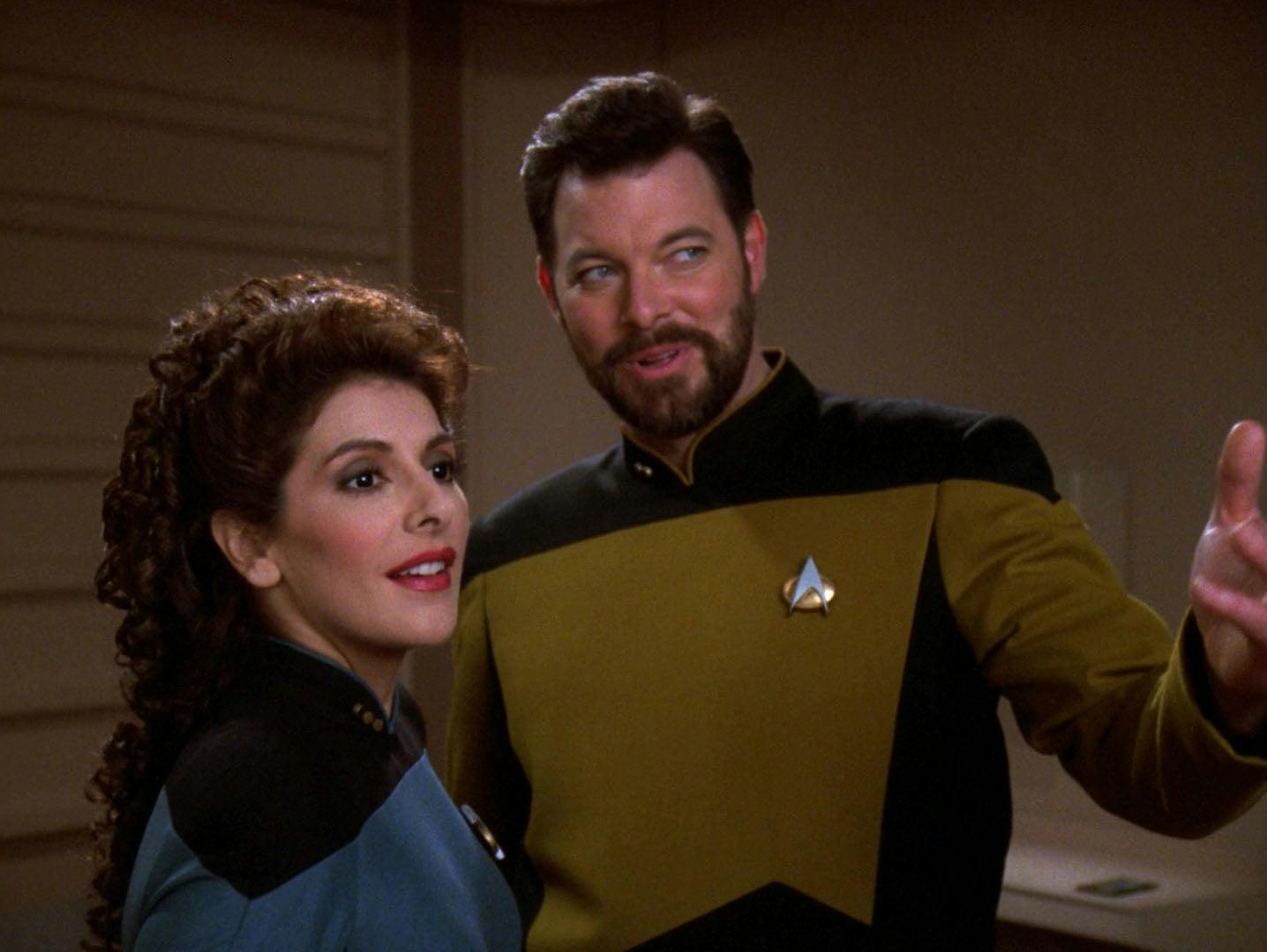 Deanna Troi and Thomas Riker side-by-side, smiling as they look ahead in 'Second Chances'