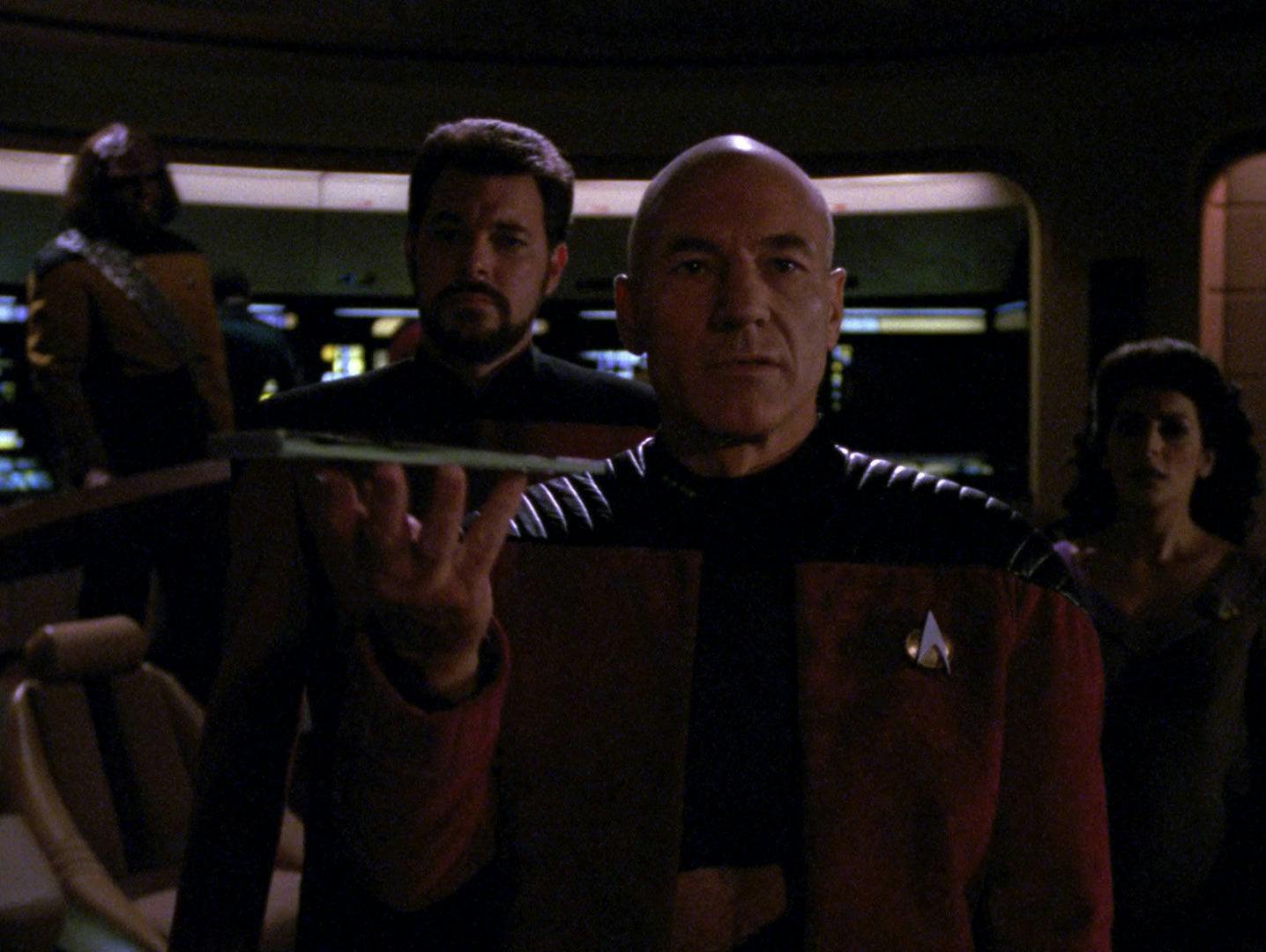 On the bridge of the Enterprise-D, Picard stands addressing the ship's viewscreen as Riker, Deanna Troi, and Worf stand behind him in 'Darmok'