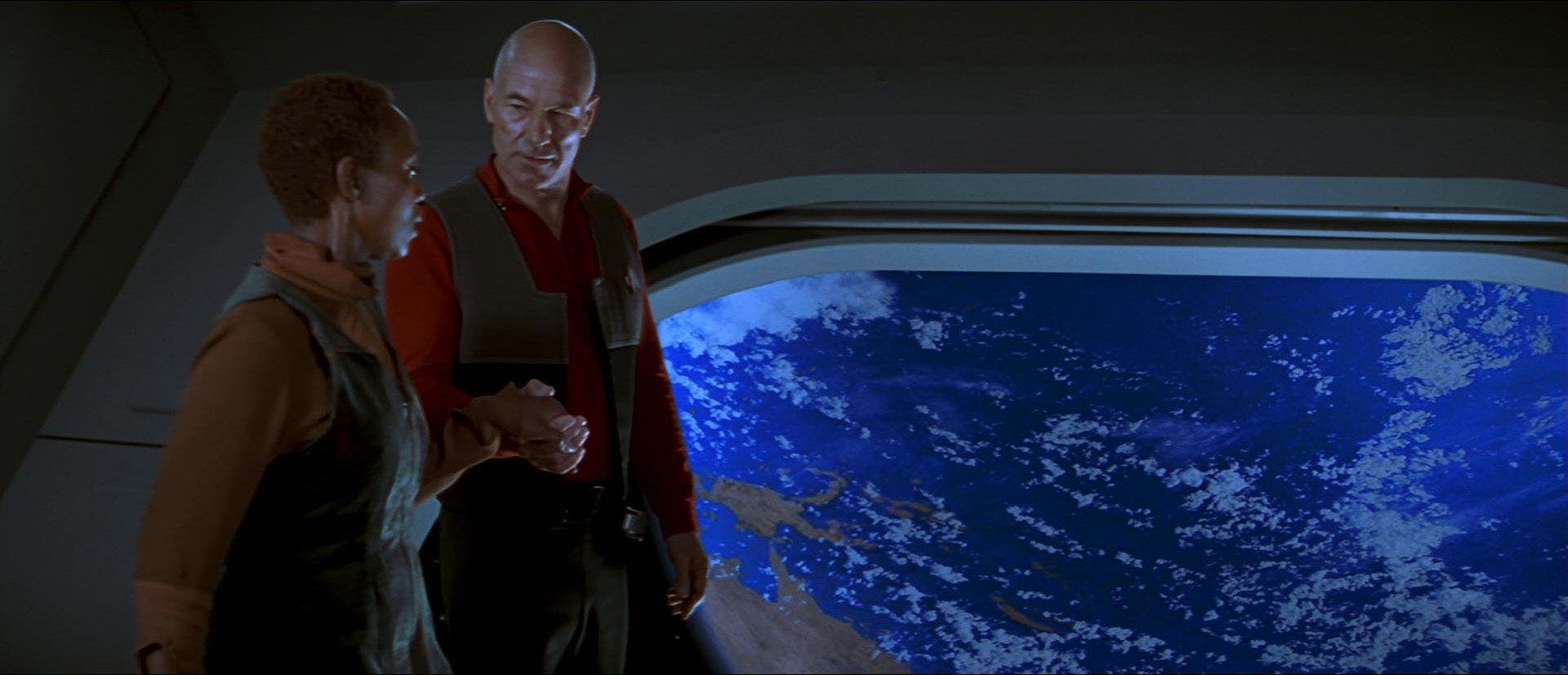 Picard holds Lily Sloane's hand as he escorts her around the Enterprise as she looks out the window at Earth below them in Star Trek: First Contact