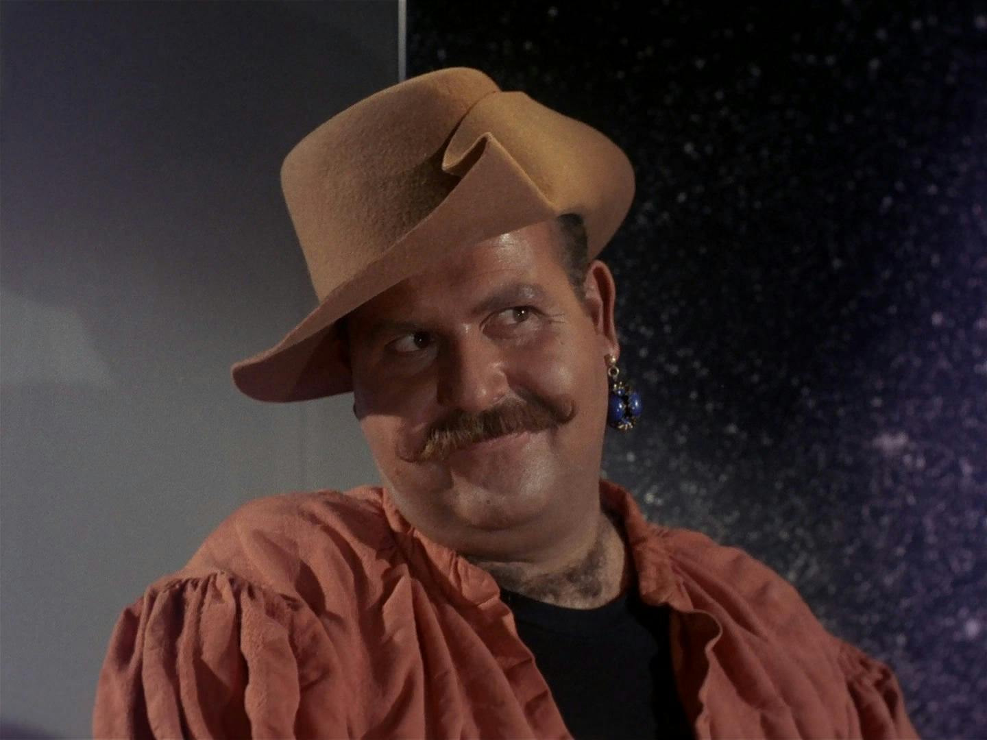 A close-up of Harry Mudd as he cheekily tilts his head towards his shoulder while looking over in Star Trek: The Original Series' 'Mudd's Women'