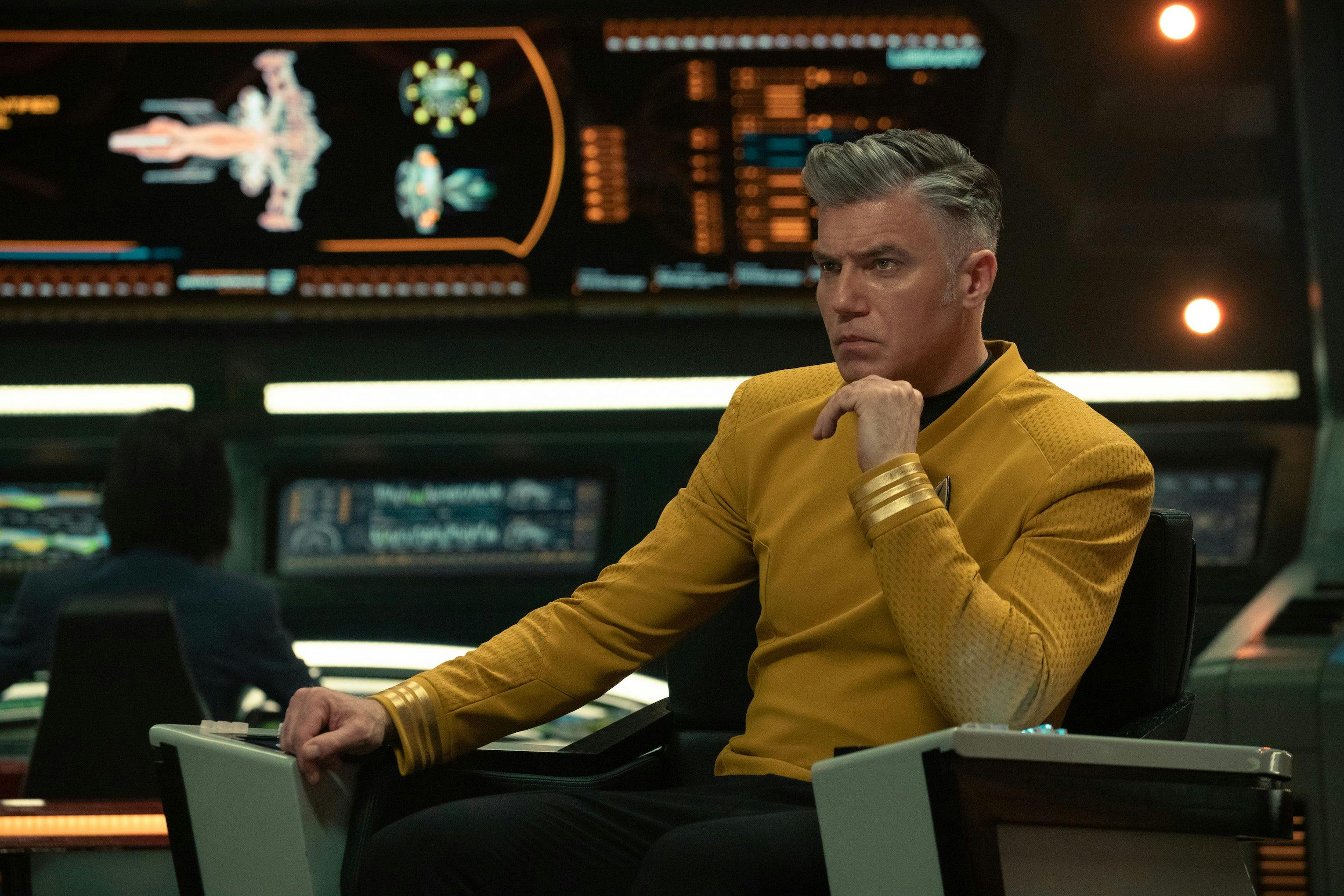 A focused Christopher Pike sits in the captain's chair on the bridge and rests his chin on his left hand