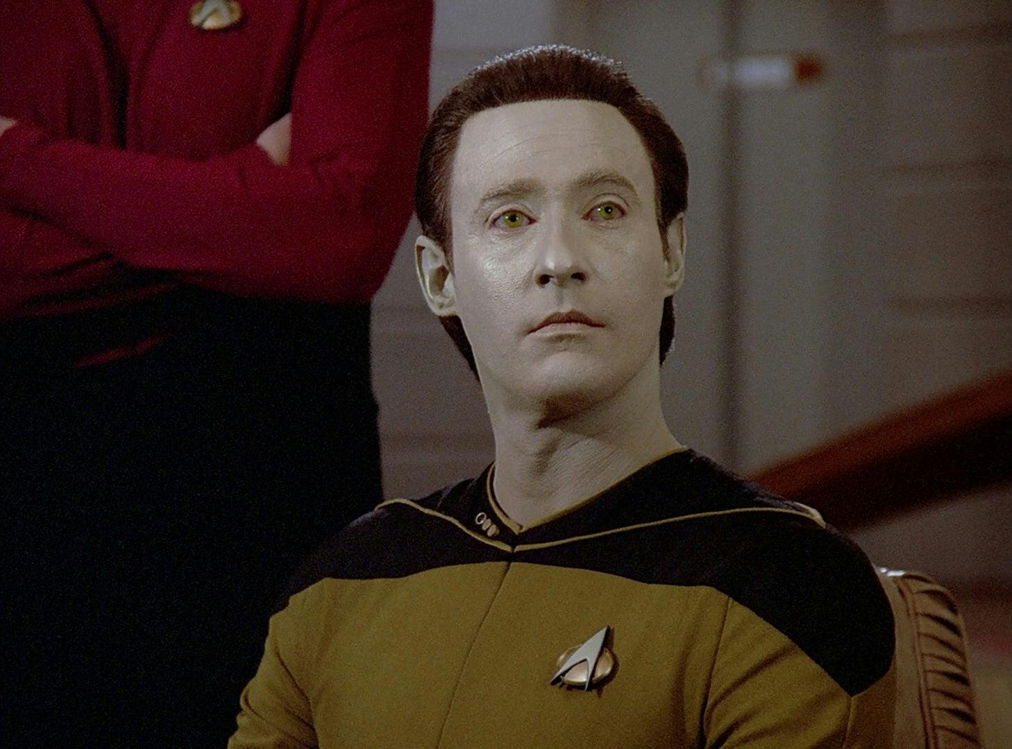 Data sits at his post on the bridge.