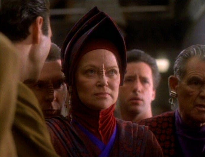 From the crowd on the Promenade, Vedek Winn coldly looks ahead towards Commander Sisko, Major Kira, and Vedek Bareil in 'In the Hands of the Prophets'