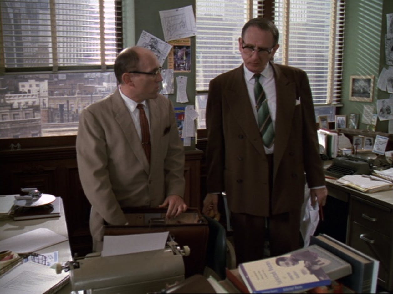 Herbert Rossoff (Quark) and Douglas Pabst (Odo) stand side-by-side at their desks at Incredible Tales as Benny Russell's copy of Langston Hughes' collection of poems sits on top of a pile of books in 'Far Beyond the Stars'