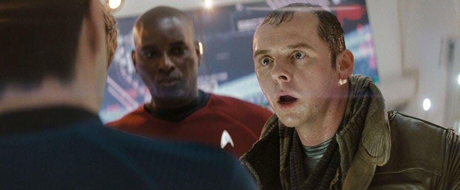 A soaking wet Scotty (Simon Pegg) stands between Kirk and Spock with a security officer behind him on the bridge of the Enterprise in Star Trek (2009)