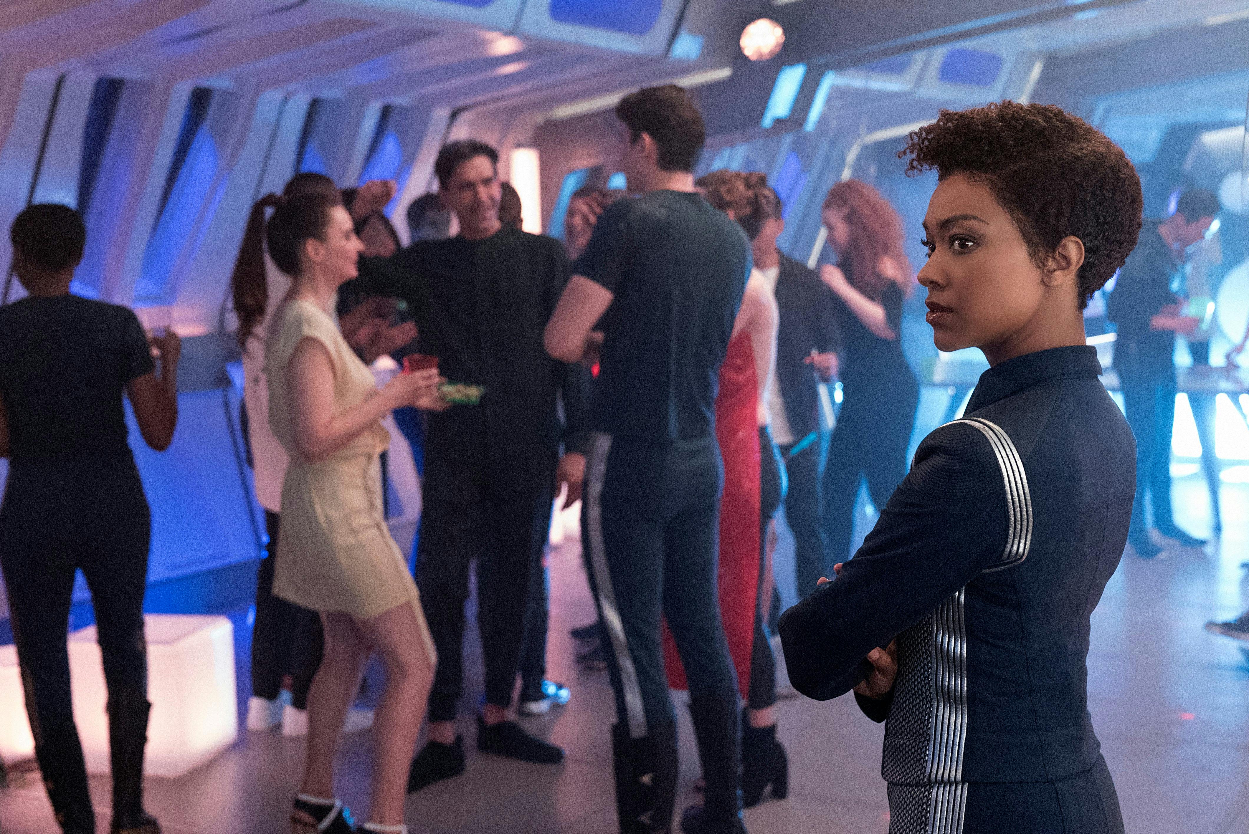 Michael Burnham stands on the sidelines at a party among crew in 'Magic to Make the Sanest Man Go Mad'