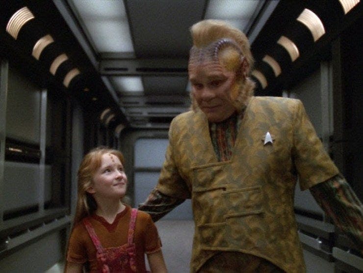 Neelix accompanies Naomi Wildman down a Voyager corridor as his hand guides her in Star Trek: Voyager's 'Once Upon A Time'