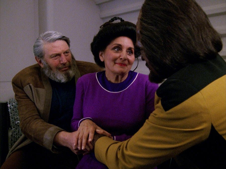 Sergey Rozhenko and his wife Helena lovingly support Worf as they clasp hands on the couch in 'Family'