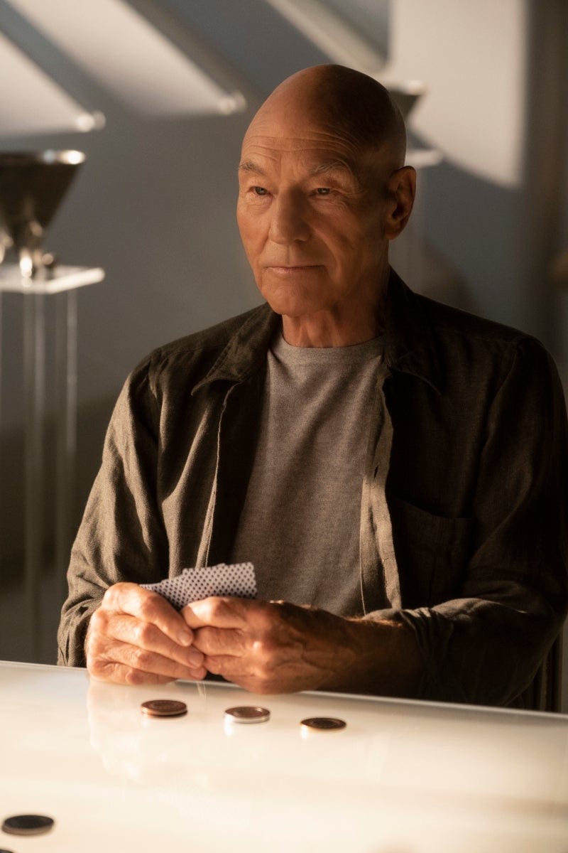 Picard holds a hand of cards with a stack of coins in front of him in 'Remembrance'