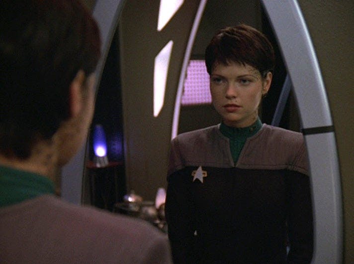 Ezri Dax looks at her own reflection.