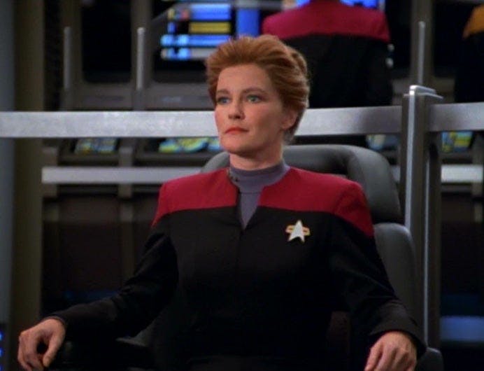 Janeway sits in the captain's chair on the bridge of Voyager in 'Caretaker'